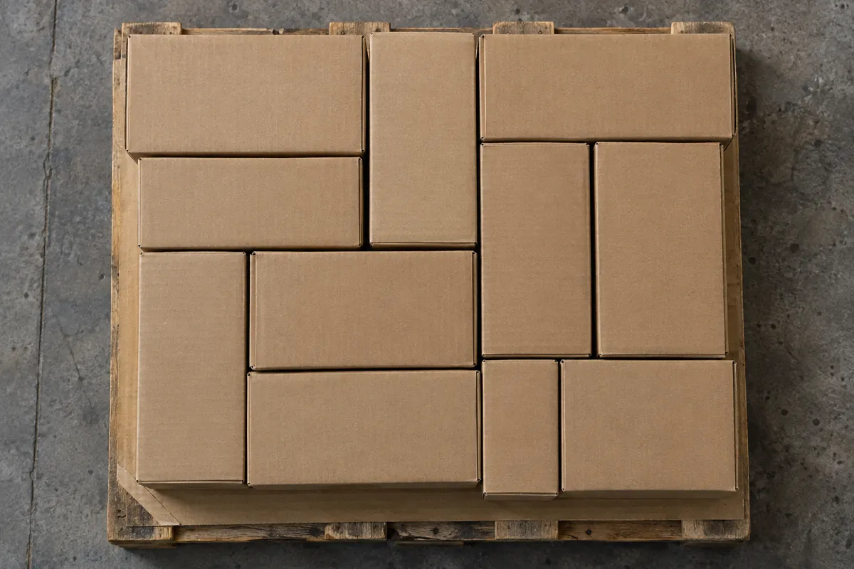 Top-down view of a pallet layer made of plain brown cartons arranged in an interlocked pattern with some cartons turned sideways